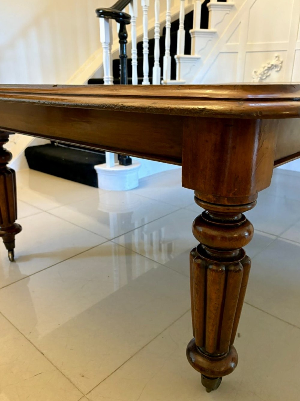 A large Victorian mahogany extending dining table with a polished surface, moulded rim, additional leaves, and turned fluted legs on brass castors. View XII