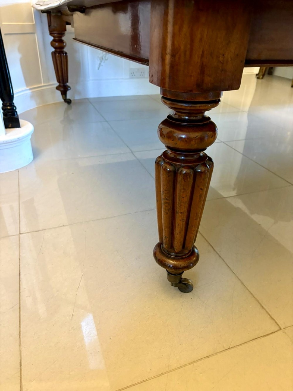 A large Victorian mahogany extending dining table with a polished surface, moulded rim, additional leaves, and turned fluted legs on brass castors. View XIII