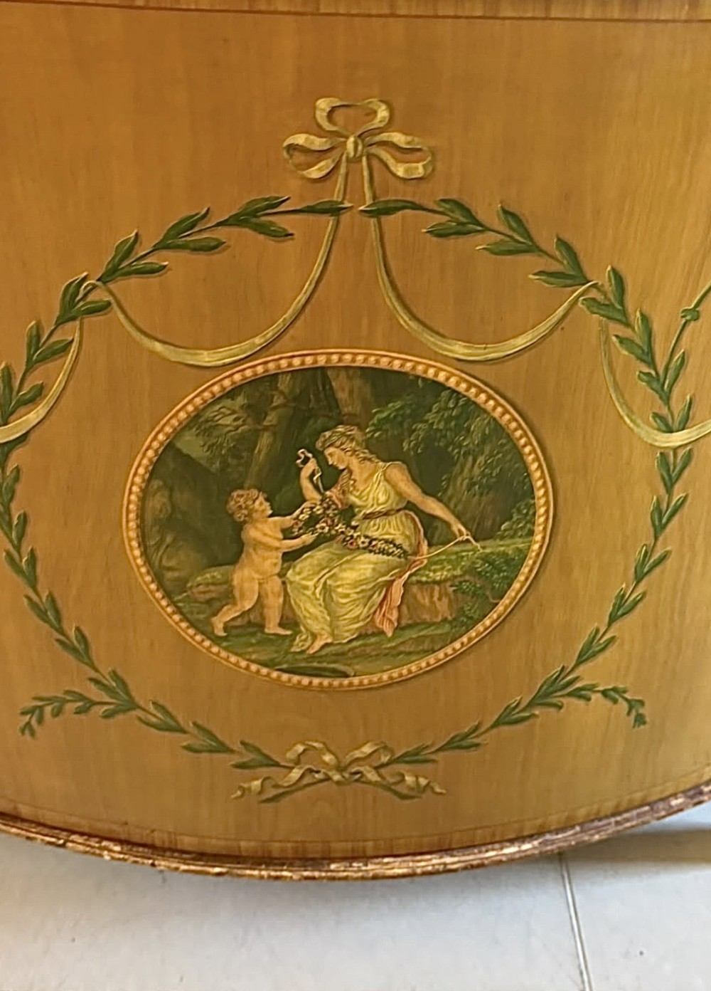 A semicircular satinwood demi-lune cabinet featuring hand-painted neoclassical leaf swags, a central figural medallion, and short tapered feet. View XIII