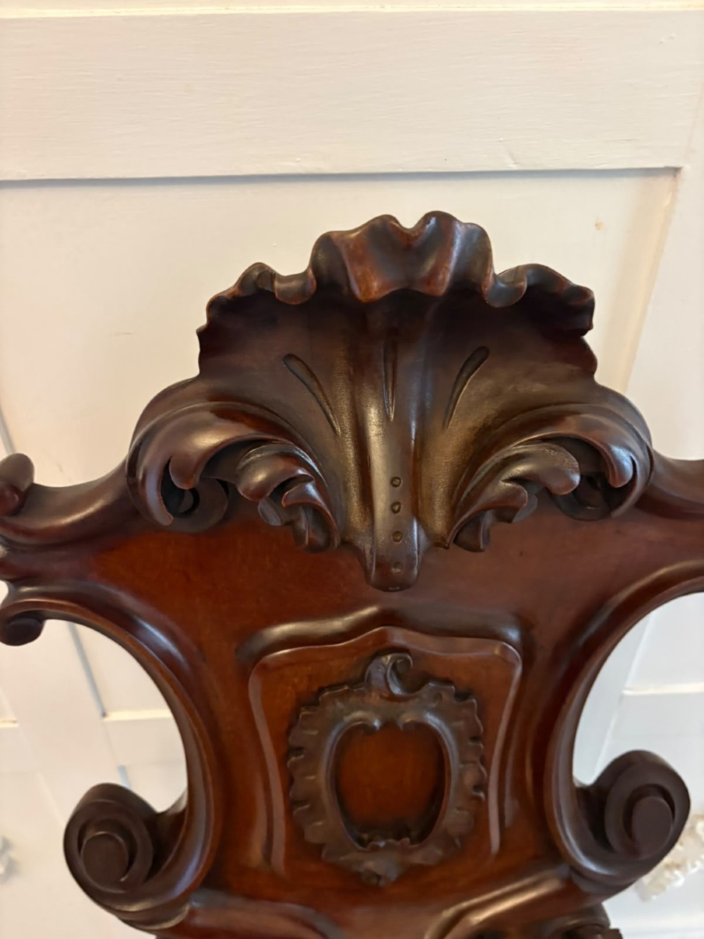 A pair of Victorian carved mahogany hall chairs with shaped timber seats, scrolled cartouche backrests, and carved cabriole legs. View VIII