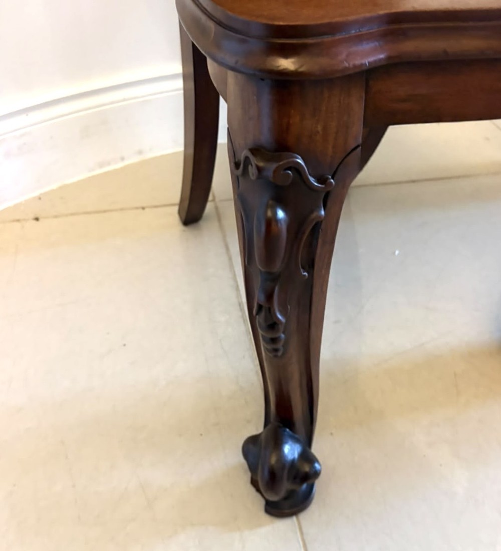 A pair of Victorian carved mahogany hall chairs with shaped timber seats, scrolled cartouche backrests, and carved cabriole legs. View X