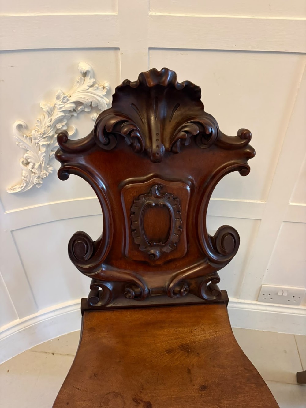 A pair of Victorian carved mahogany hall chairs with shaped timber seats, scrolled cartouche backrests, and carved cabriole legs. View XIII