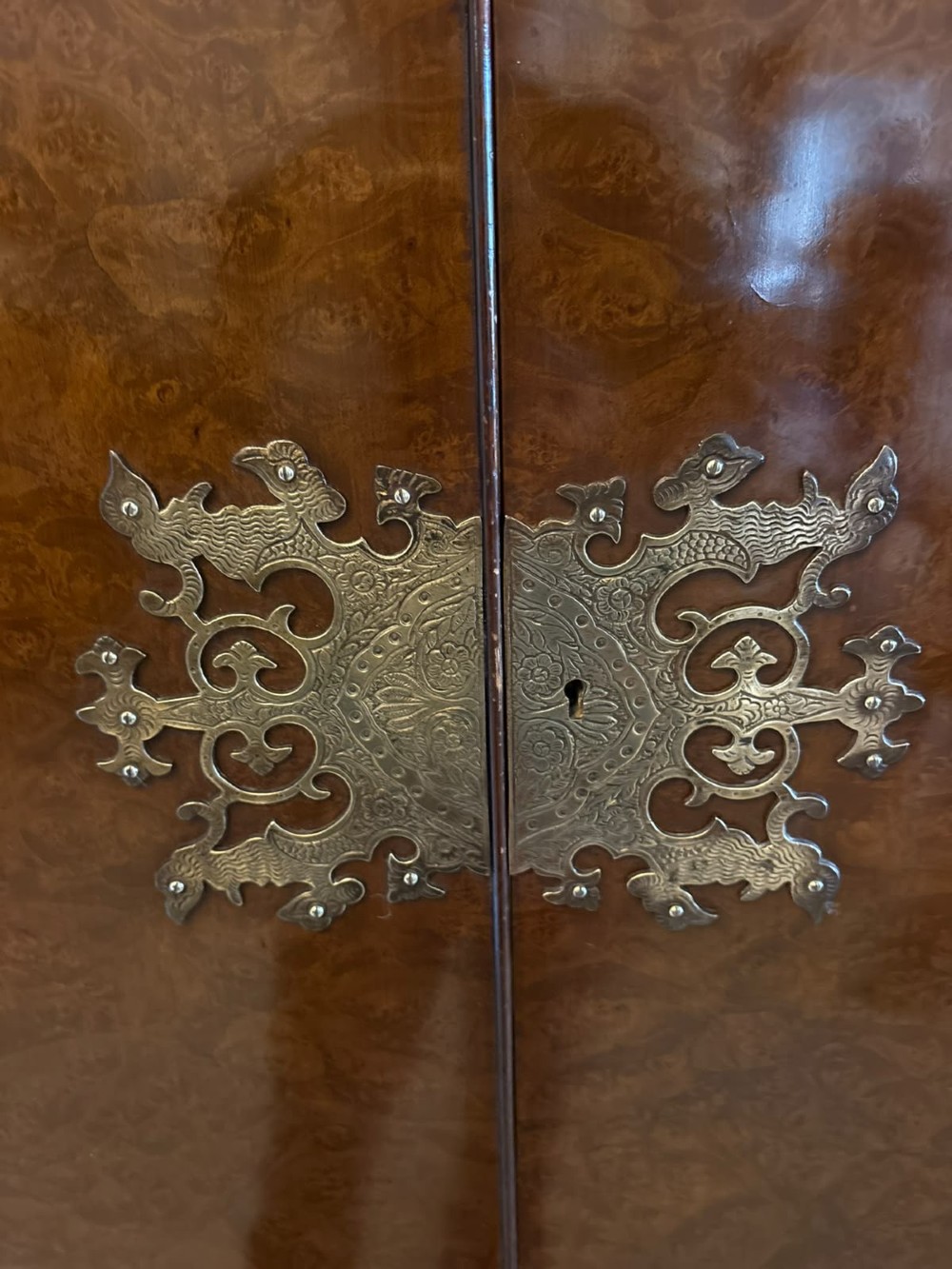 An antique burr walnut cocktail cabinet featuring decorative brass hardware, carved scroll cresting, two cupboard sections, and cabriole legs. View II