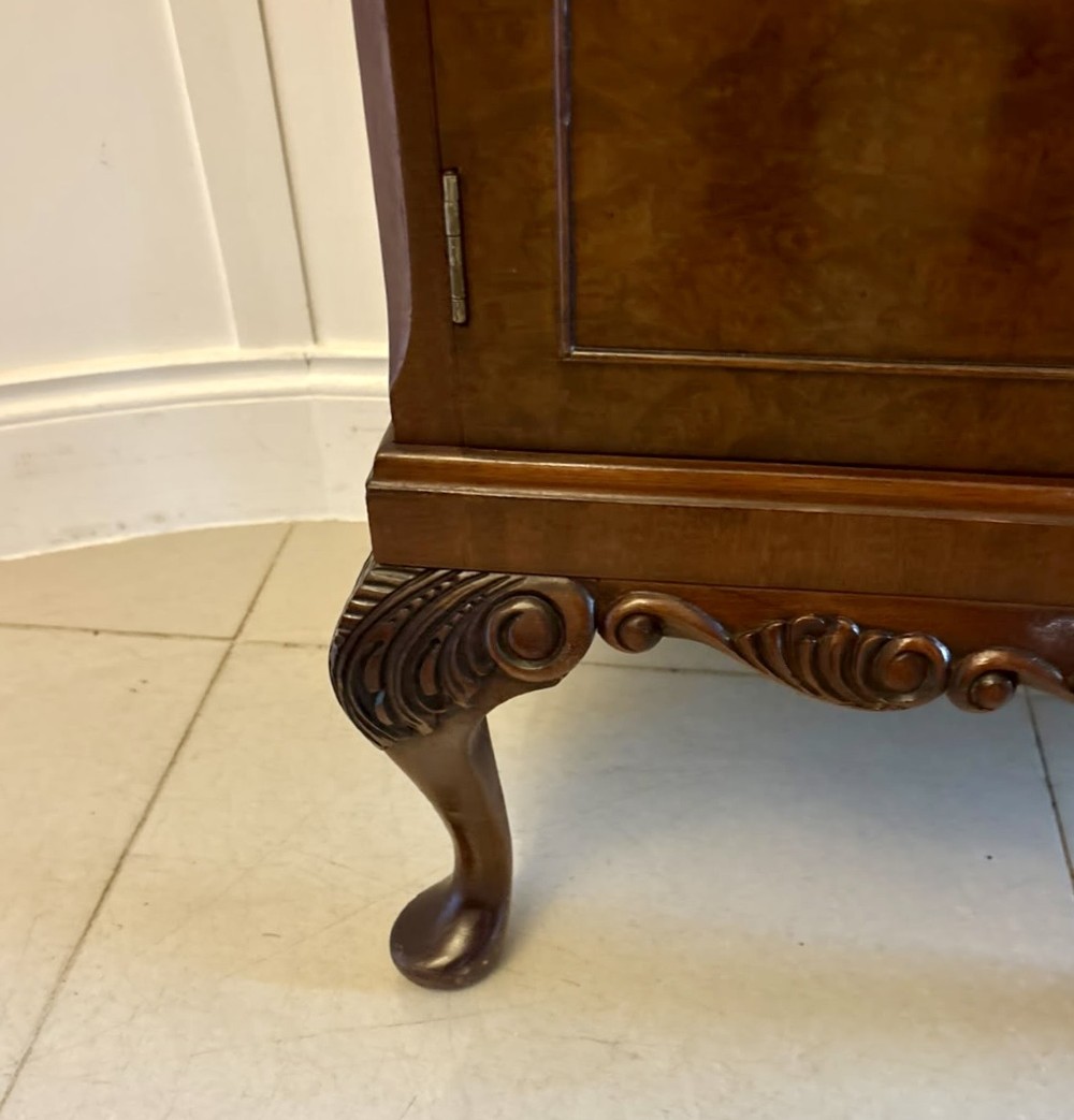 An antique burr walnut cocktail cabinet featuring decorative brass hardware, carved scroll cresting, two cupboard sections, and cabriole legs. View III
