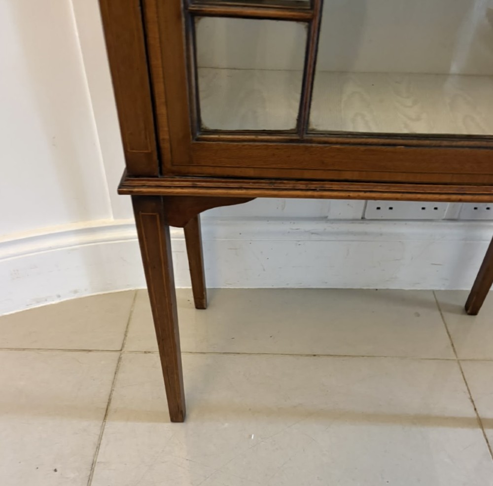 An Edwardian mahogany glazed display cabinet featuring geometric glazing bars, tapered legs, a raised pediment top, and a light-lined interior with three shelves. View V