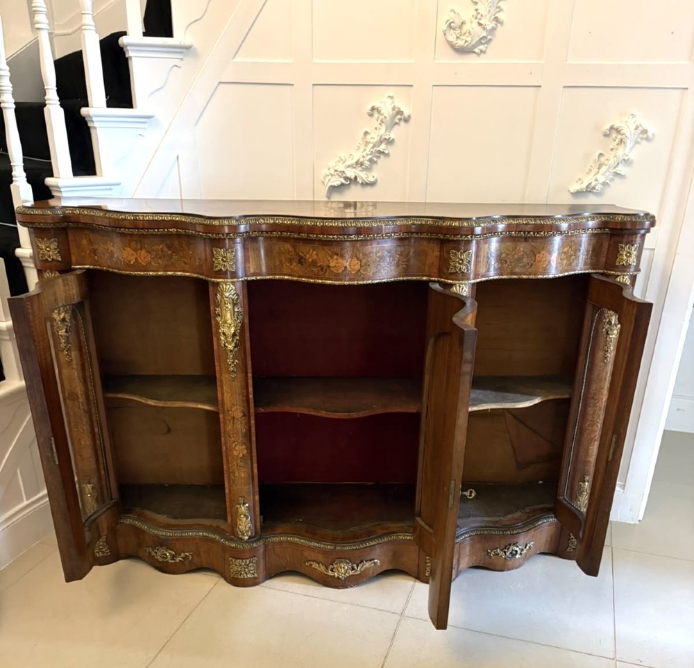 A Victorian serpentine burr walnut credenza featuring detailed floral marquetry inlays, gilt-bronze mounts, a central panelled door, and two curved glazed side doors. View VII