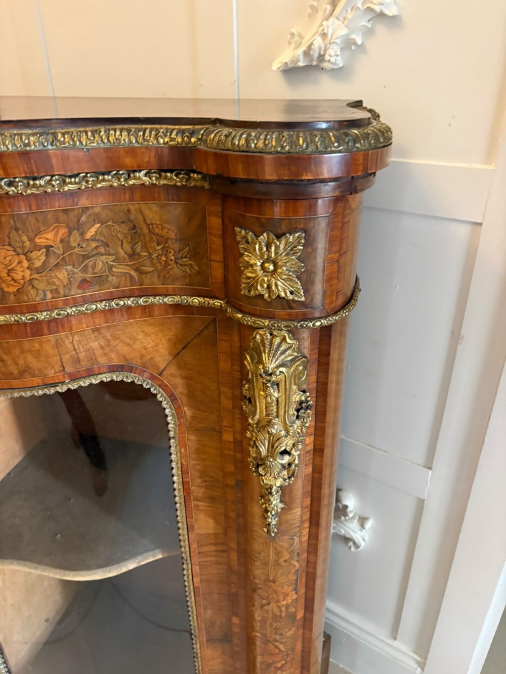A Victorian serpentine burr walnut credenza featuring detailed floral marquetry inlays, gilt-bronze mounts, a central panelled door, and two curved glazed side doors. View XIII