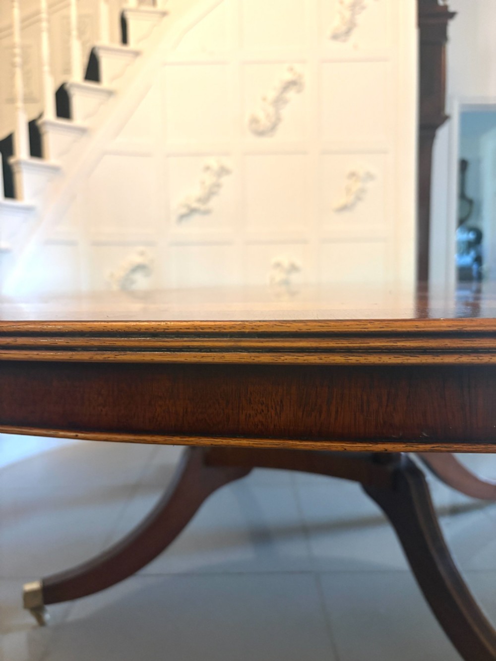 A large circular mahogany dining table featuring a yew wood crossbanded border and a central pedestal base. View V