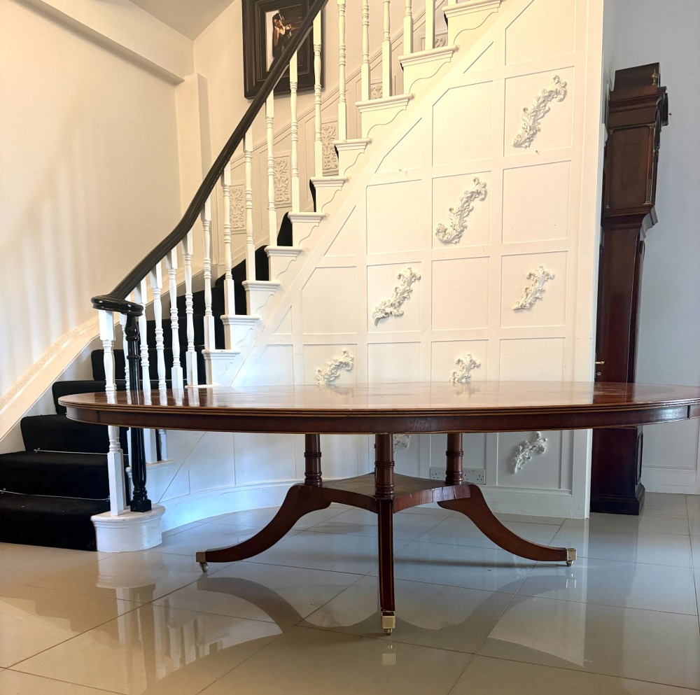 A large circular mahogany dining table featuring a yew wood crossbanded border and a central pedestal base. View IX