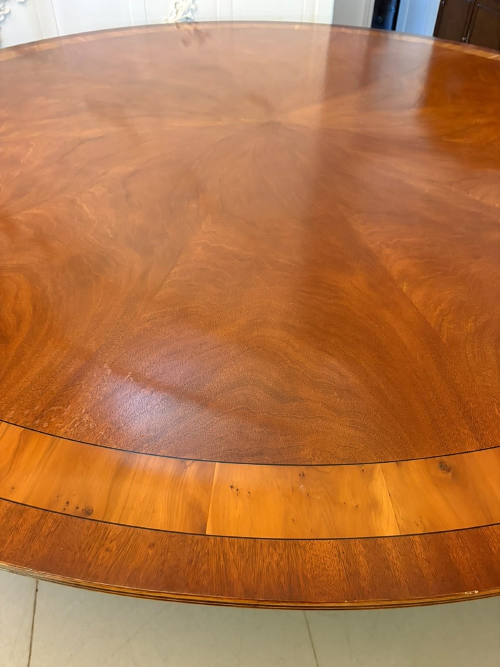 A large circular mahogany dining table featuring a yew wood crossbanded border and a central pedestal base. View X