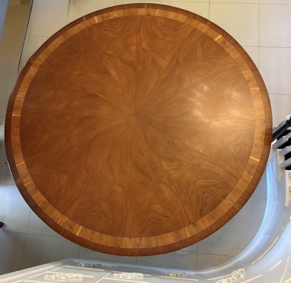 A large circular mahogany dining table featuring a yew wood crossbanded border and a central pedestal base. View XI
