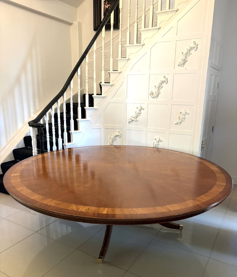 A large circular mahogany dining table featuring a yew wood crossbanded border and a central pedestal base. View XIV
