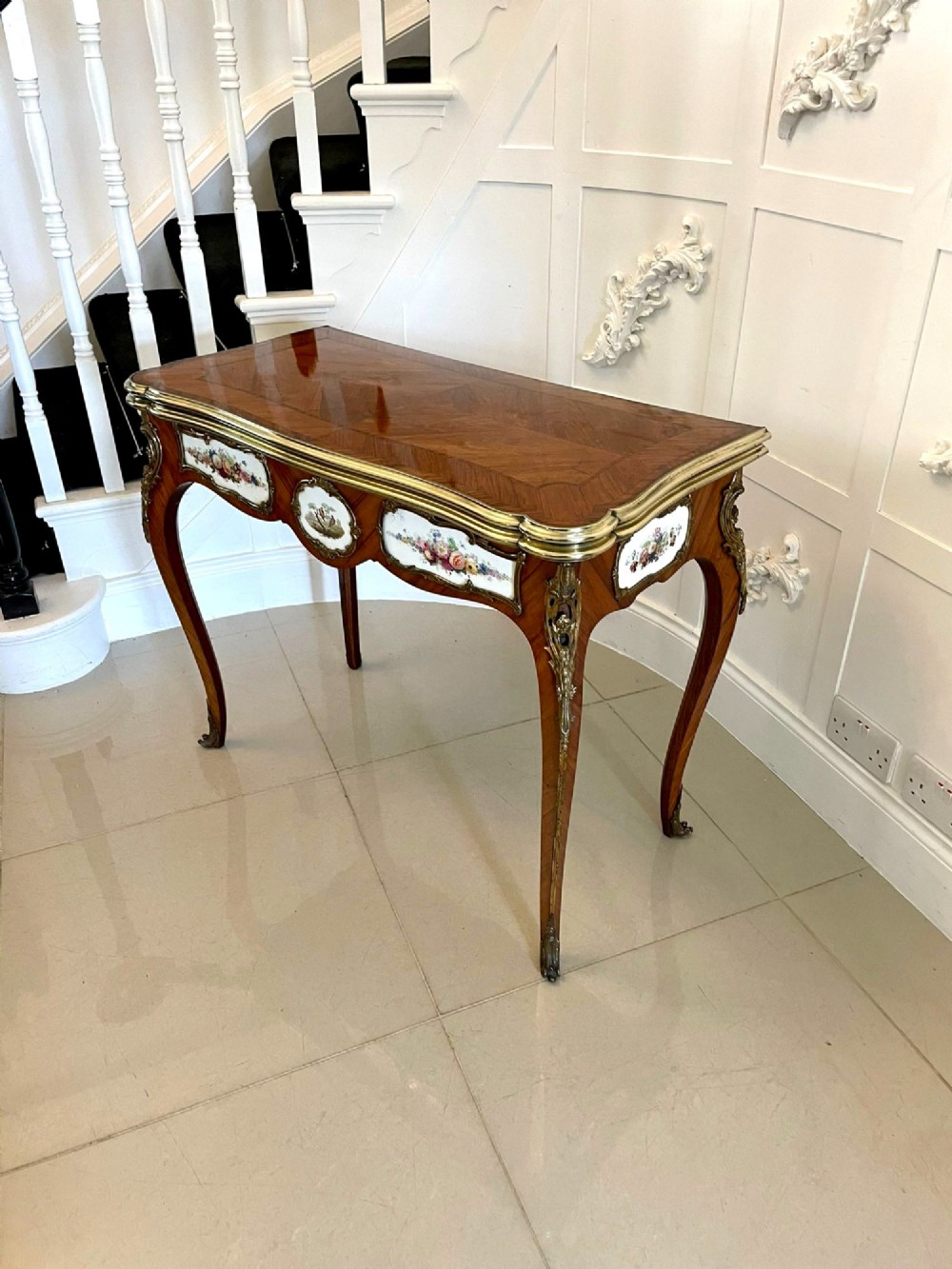 A Victorian Louis XV Revival kingwood console card table featuring a serpentine fold-over top, cabriole legs, gilt bronze mounts, and inset painted porcelain plaques. View V