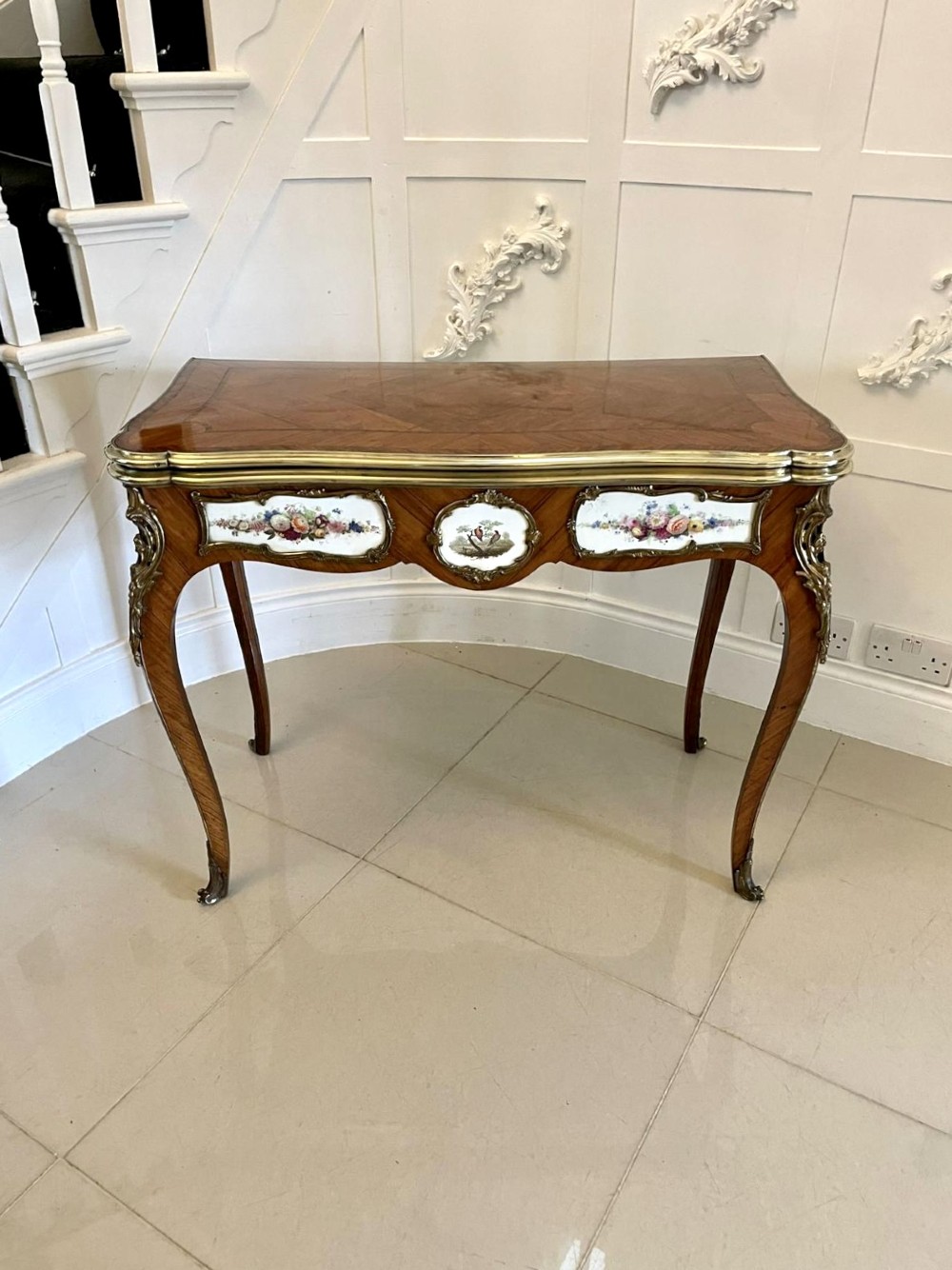 A Victorian Louis XV Revival kingwood console card table featuring a serpentine fold-over top, cabriole legs, gilt bronze mounts, and inset painted porcelain plaques.
