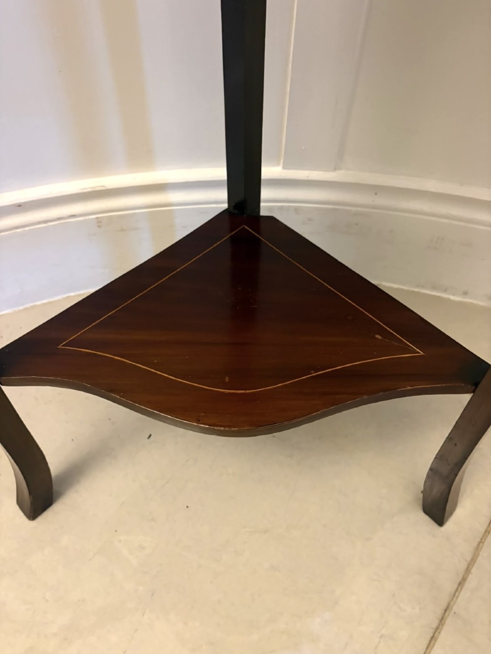 An Edwardian mahogany corner display cabinet with a serpentine glazed door, line inlay decoration, shaped upper pediment, and slender tapered legs with a lower undertier. View VI