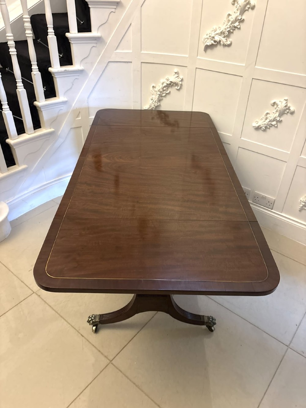 A Regency mahogany sofa table featuring two drop leaves, two front drawers with round brass knobs, reeded splayed legs, and brass paw castors. View V