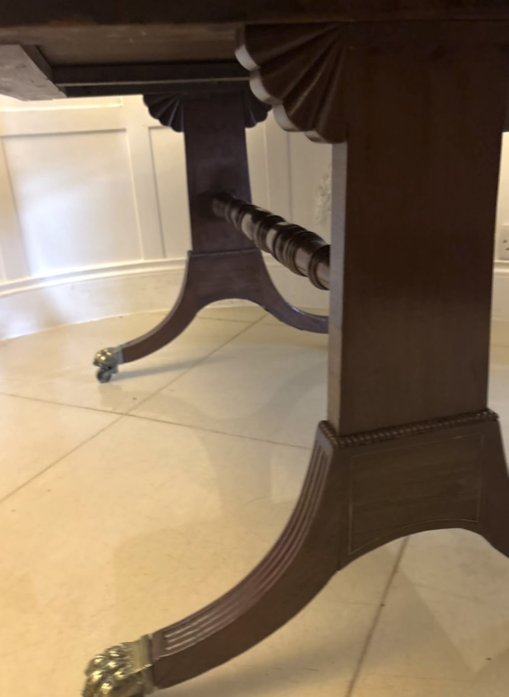 A Regency mahogany sofa table featuring two drop leaves, two front drawers with round brass knobs, reeded splayed legs, and brass paw castors. View VII
