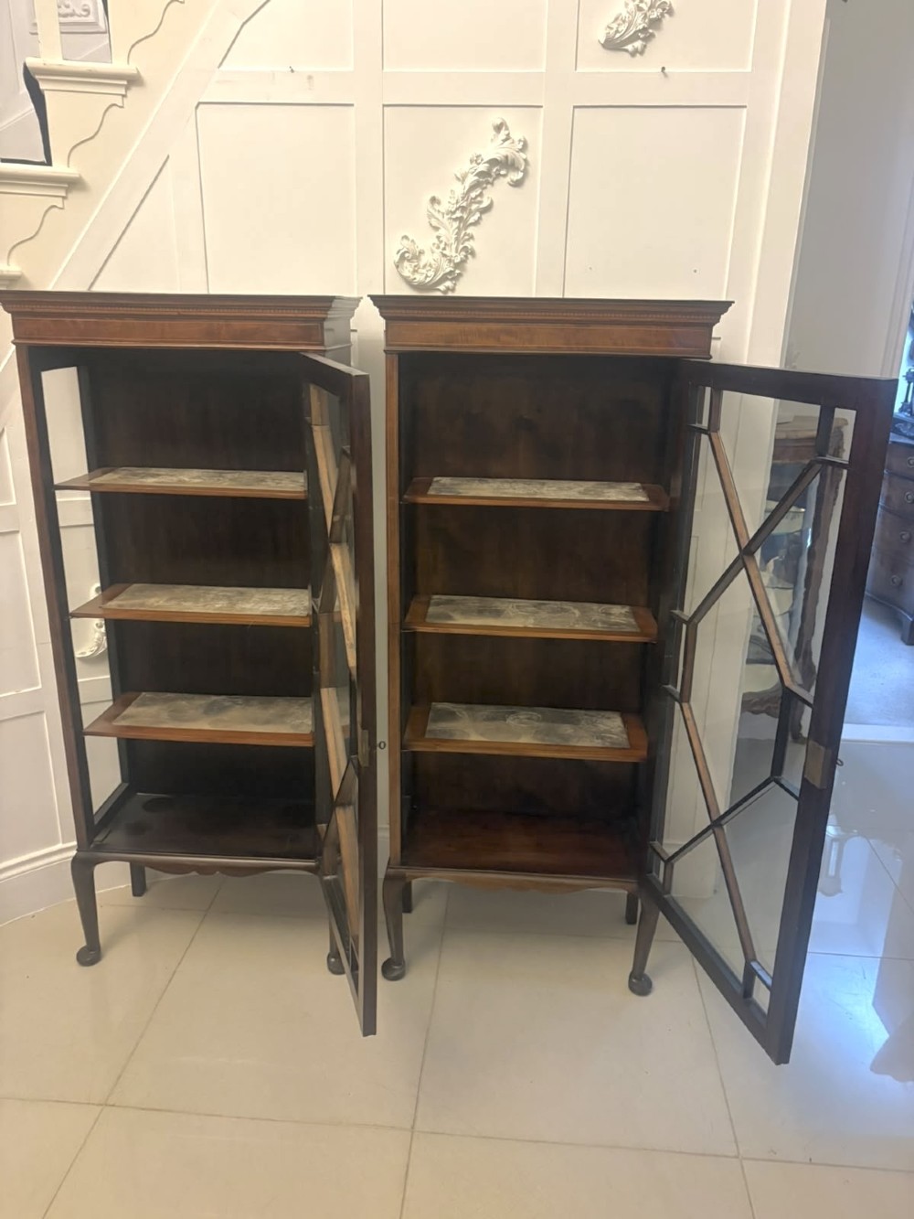 A pair of tall Edwardian mahogany display cabinets with geometric astragal glazed glass doors and slender cabriole legs. View III