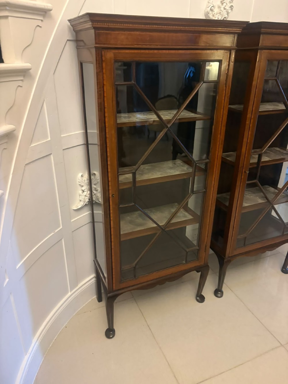 A pair of tall Edwardian mahogany display cabinets with geometric astragal glazed glass doors and slender cabriole legs. View XIII