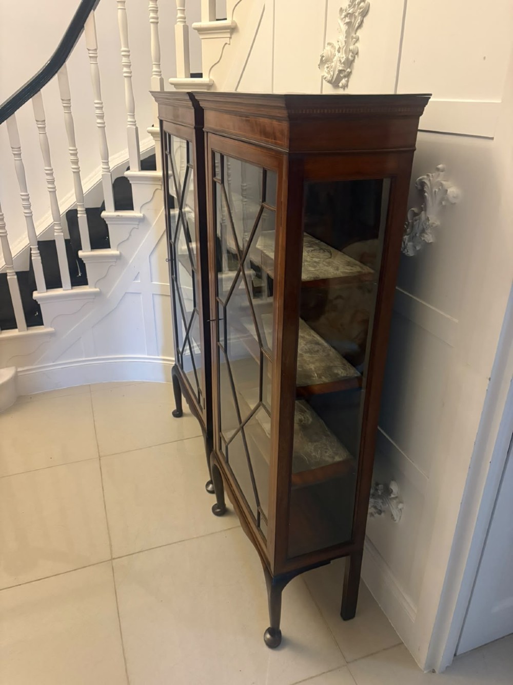 A pair of tall Edwardian mahogany display cabinets with geometric astragal glazed glass doors and slender cabriole legs. View XIV