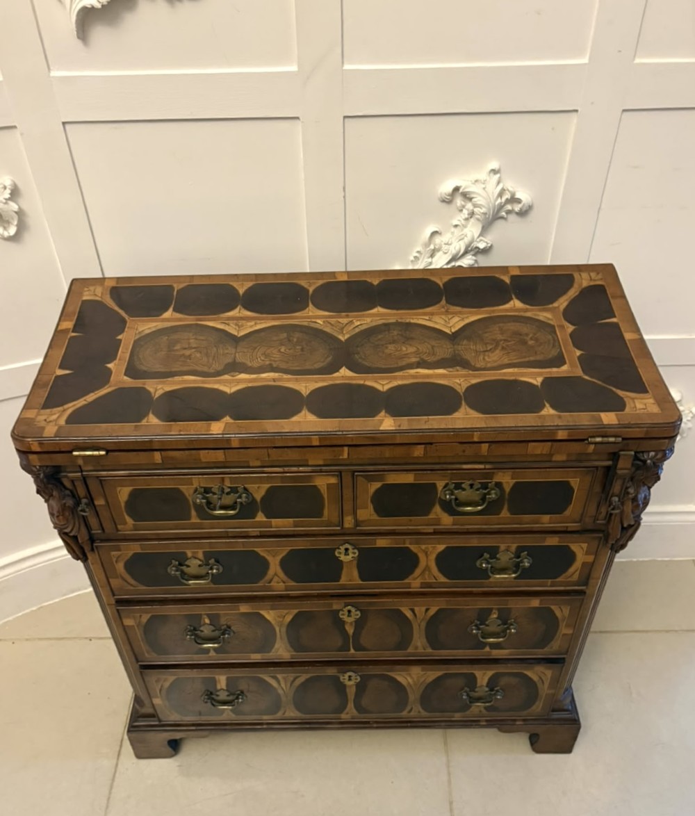 A George I yew wood and laburnum oyster veneered bachelors chest of drawers with carved corner caryatids and brass drop handles. View X