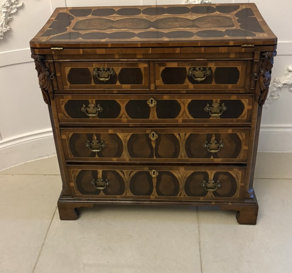 A George I yew wood and laburnum oyster veneered bachelors chest of drawers with carved corner caryatids and brass drop handles. View II