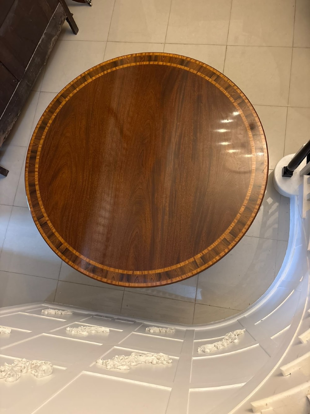 A large circular mahogany dining table featuring rosewood and satinwood crossbanding set upon a central pedestal base with reeded legs ending in brass castors. View II