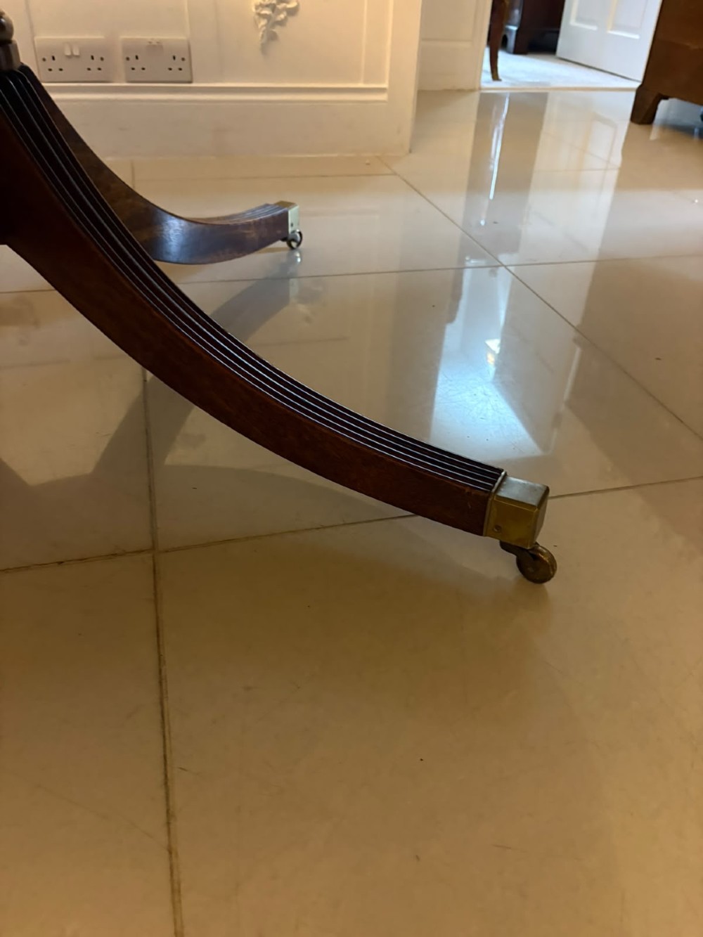 A large circular mahogany dining table featuring rosewood and satinwood crossbanding set upon a central pedestal base with reeded legs ending in brass castors. View VIII