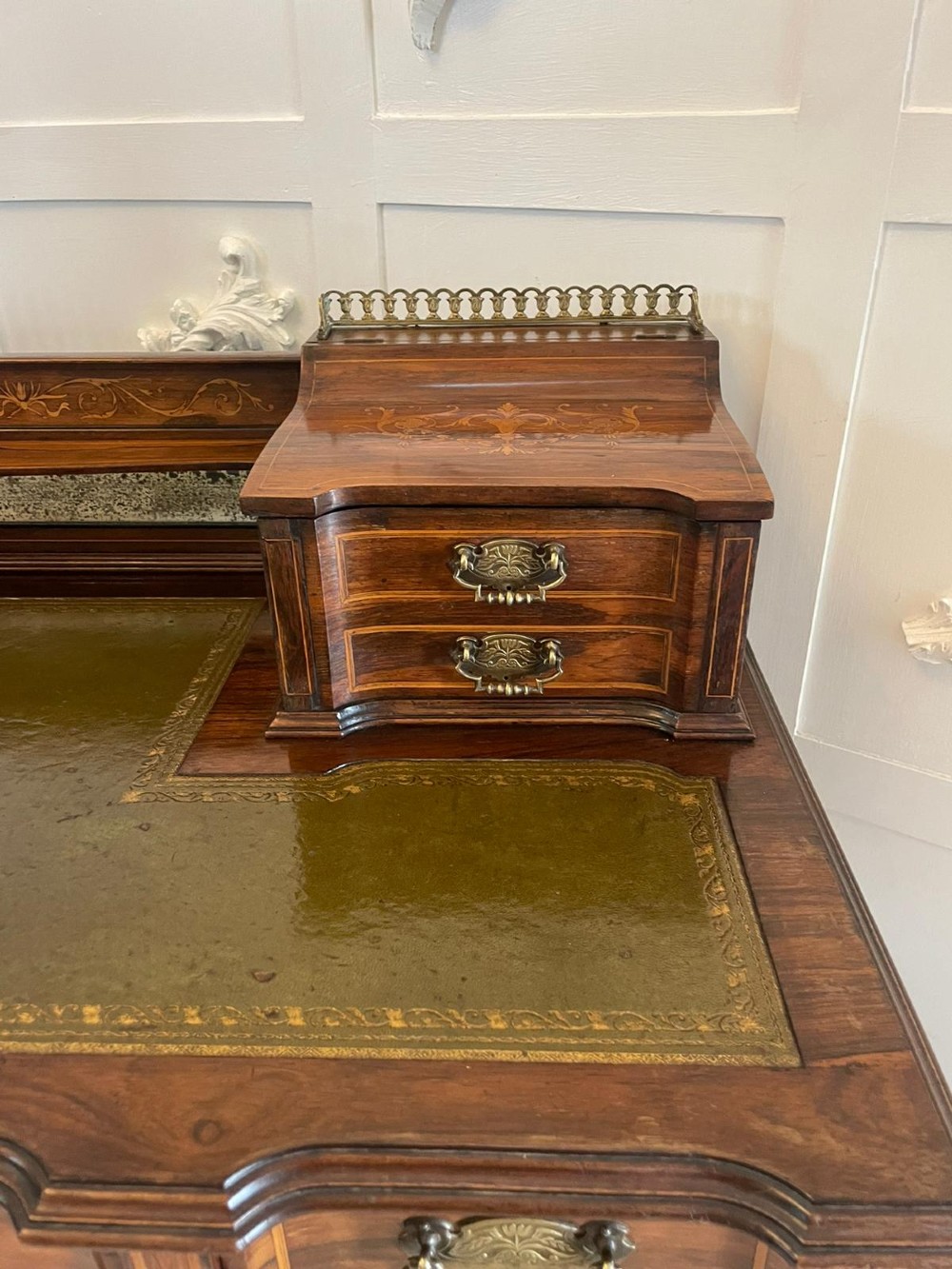A late Victorian inlaid writing desk with a dark rosewood veneer, green leather top insert, brass gallery rail, and multiple drawers on tapered legs. View VII