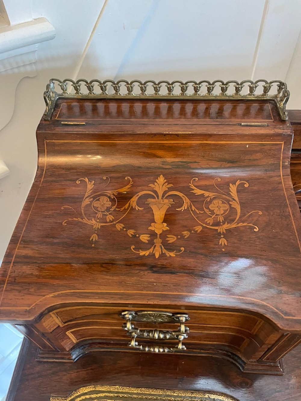 A late Victorian inlaid writing desk with a dark rosewood veneer, green leather top insert, brass gallery rail, and multiple drawers on tapered legs. View VIII