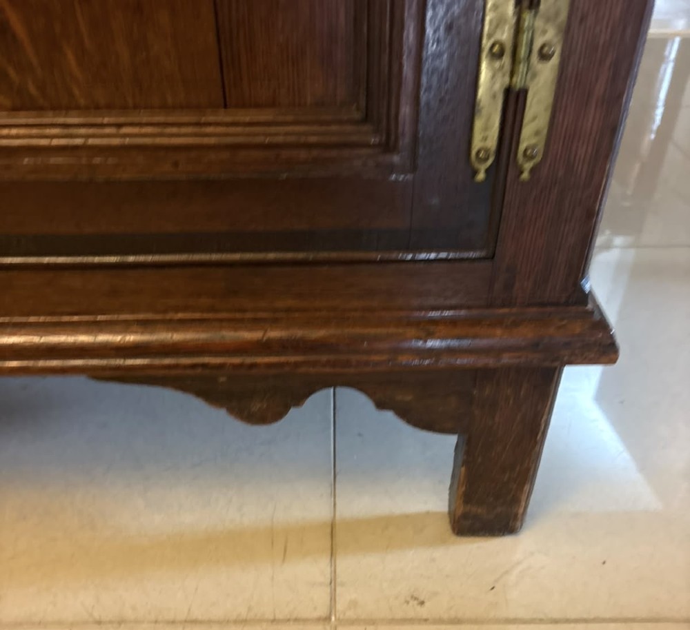 An antique dark oak Georgian dresser base featuring geometric panel drawers, brass handles, side cupboard doors, and a smooth wooden surface. View IV