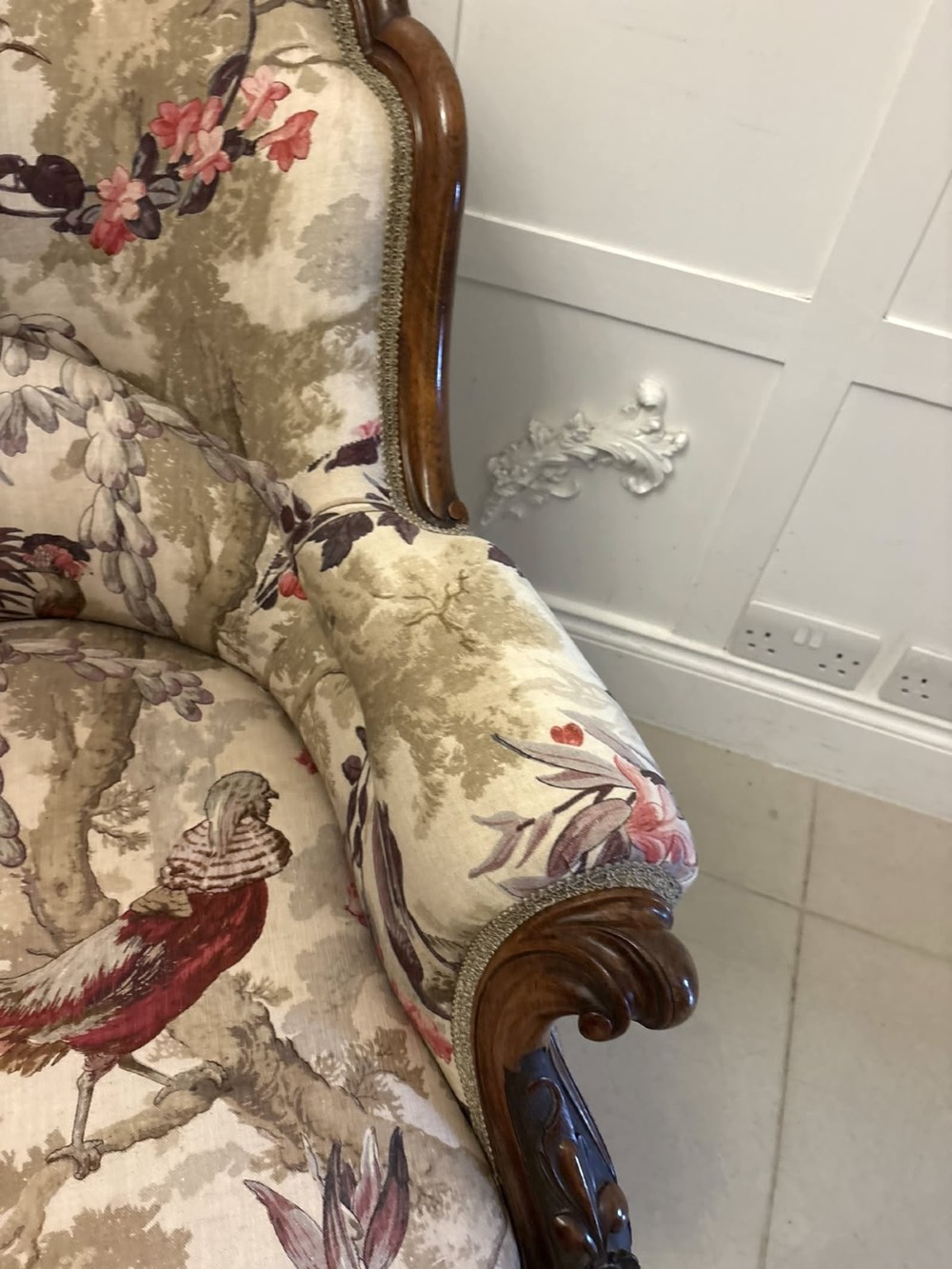 An antique Victorian carved rosewood armchair featuring floral and bird pattern upholstery with cabriole legs on castors. View VI