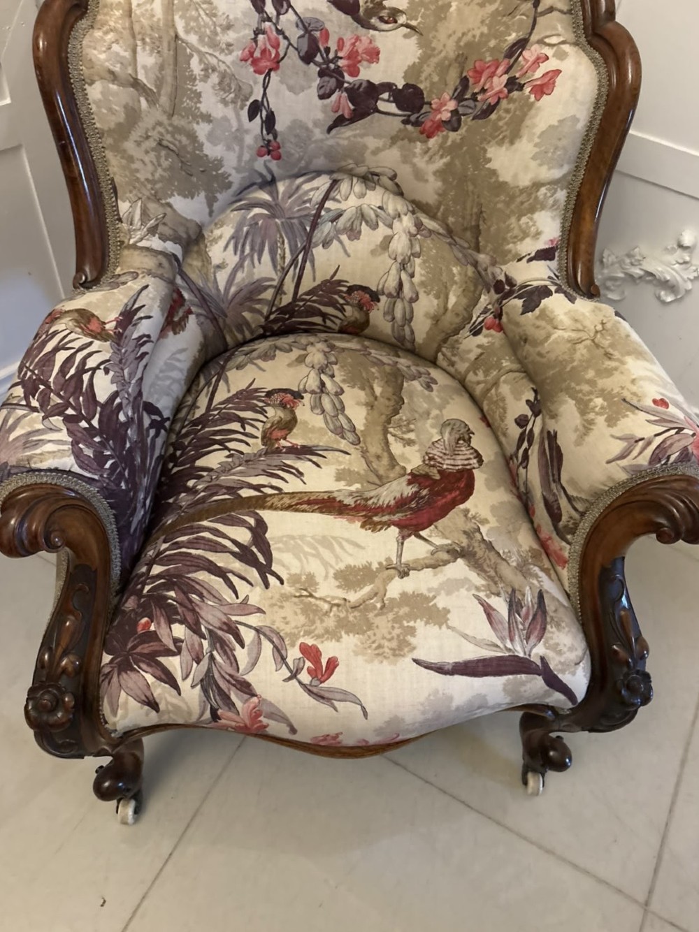 An antique Victorian carved rosewood armchair featuring floral and bird pattern upholstery with cabriole legs on castors. View VII