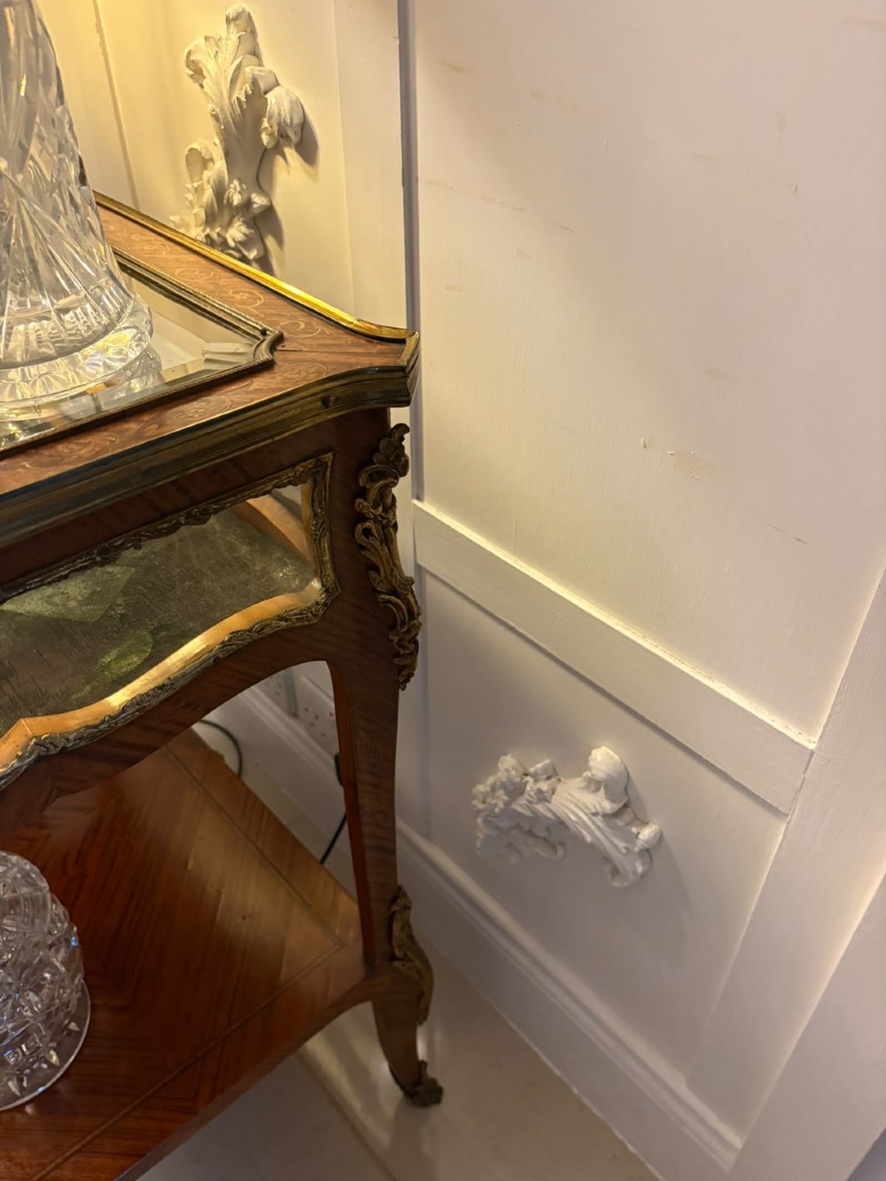 An antique French Napoleon III satinwood bijouterie table featuring a glazed display top, curved cabriole legs with decorative brass mounts, and an undertier shelf. View V