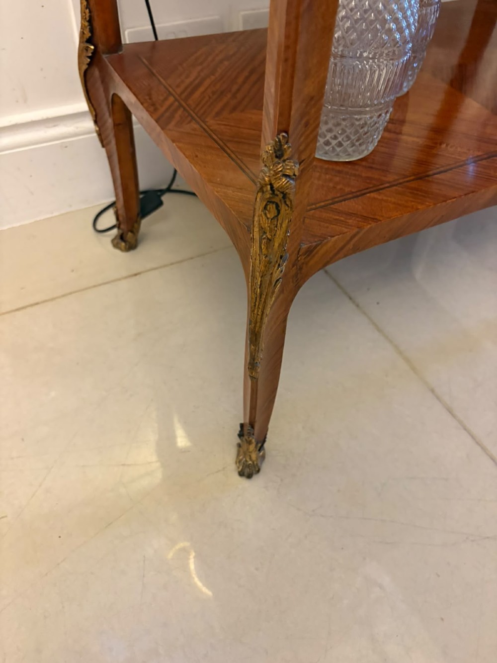 An antique French Napoleon III satinwood bijouterie table featuring a glazed display top, curved cabriole legs with decorative brass mounts, and an undertier shelf. View VIII