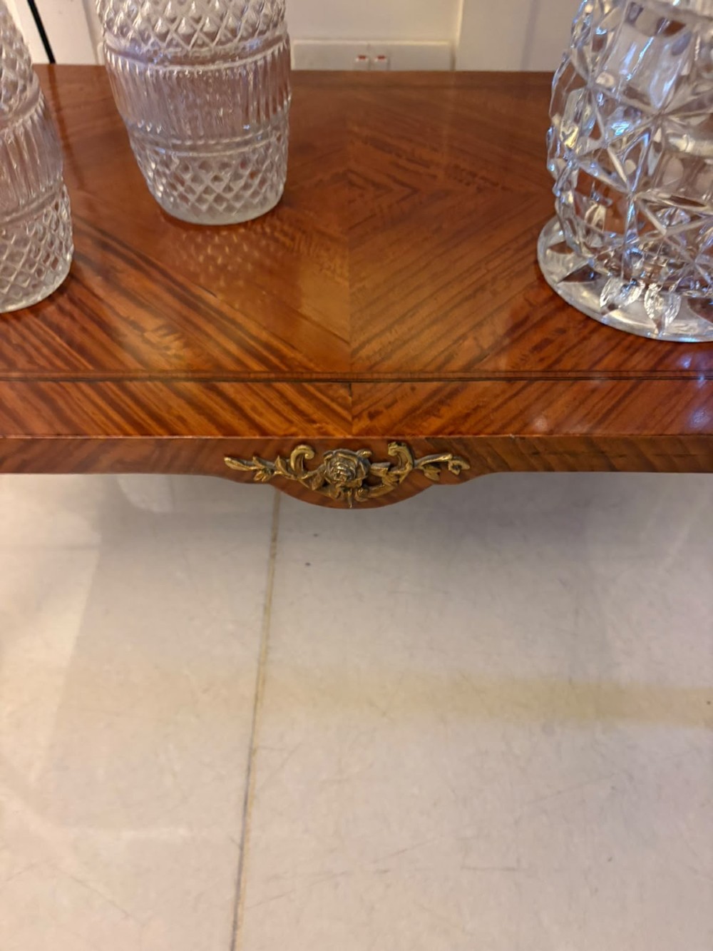 An antique French Napoleon III satinwood bijouterie table featuring a glazed display top, curved cabriole legs with decorative brass mounts, and an undertier shelf. View IX