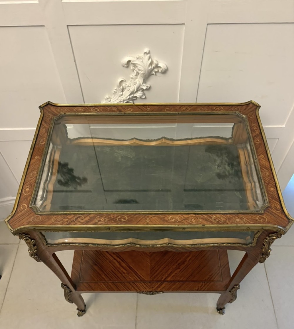 An antique French Napoleon III satinwood bijouterie table featuring a glazed display top, curved cabriole legs with decorative brass mounts, and an undertier shelf. View XIII