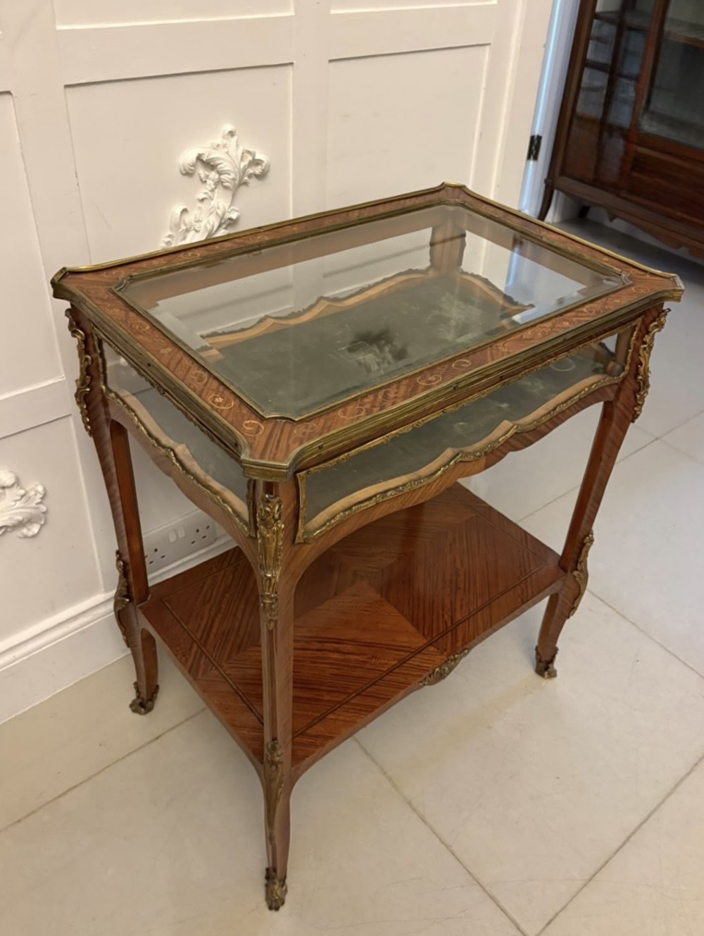 An antique French Napoleon III satinwood bijouterie table featuring a glazed display top, curved cabriole legs with decorative brass mounts, and an undertier shelf. View XIV