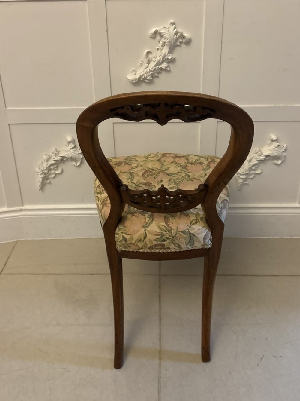 A set of four Victorian carved walnut dining chairs featuring open balloon backs, carved crest details, cabriole front legs, and floral pattern upholstered seats. View II
