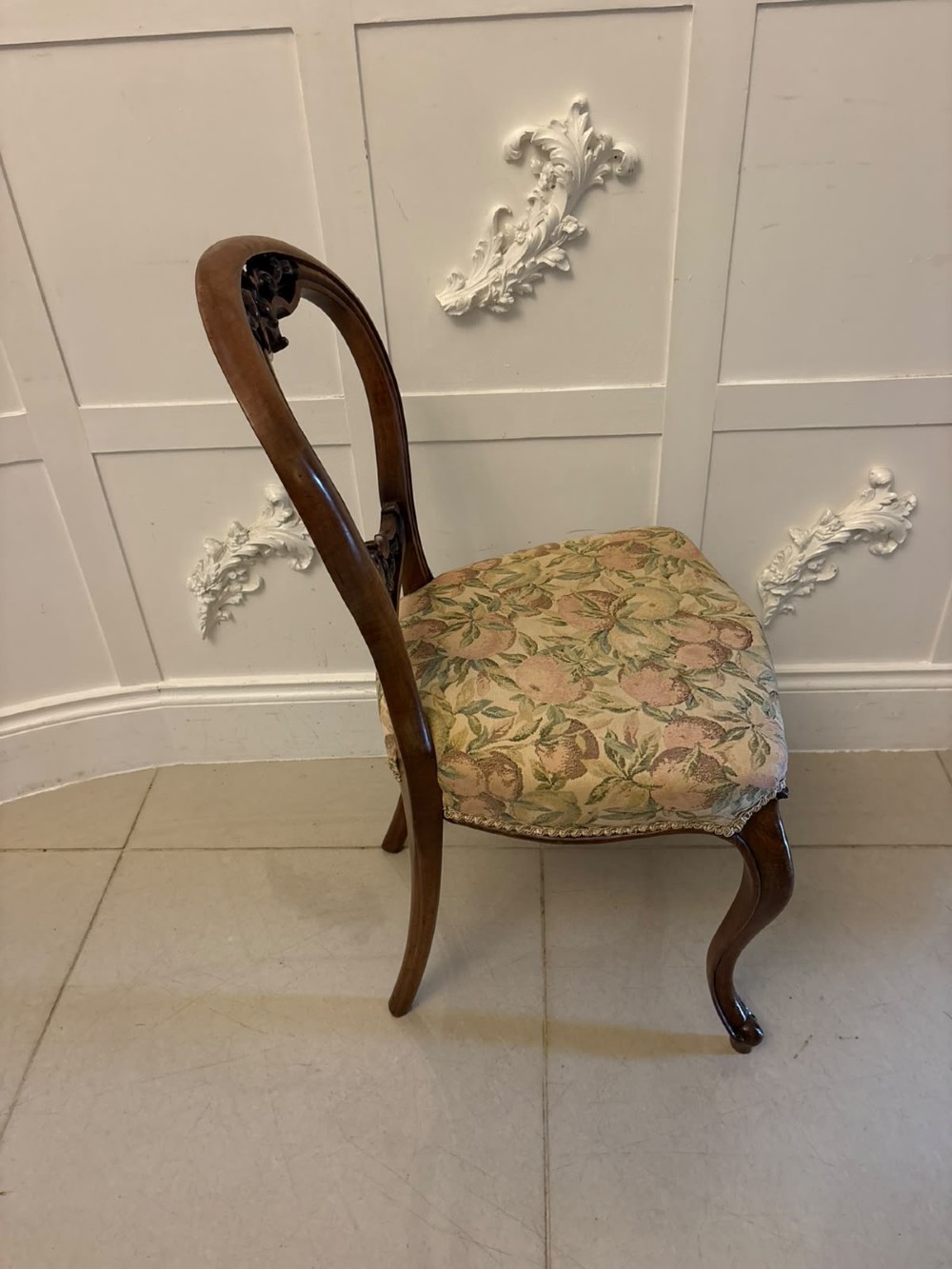 A set of four Victorian carved walnut dining chairs featuring open balloon backs, carved crest details, cabriole front legs, and floral pattern upholstered seats. View III