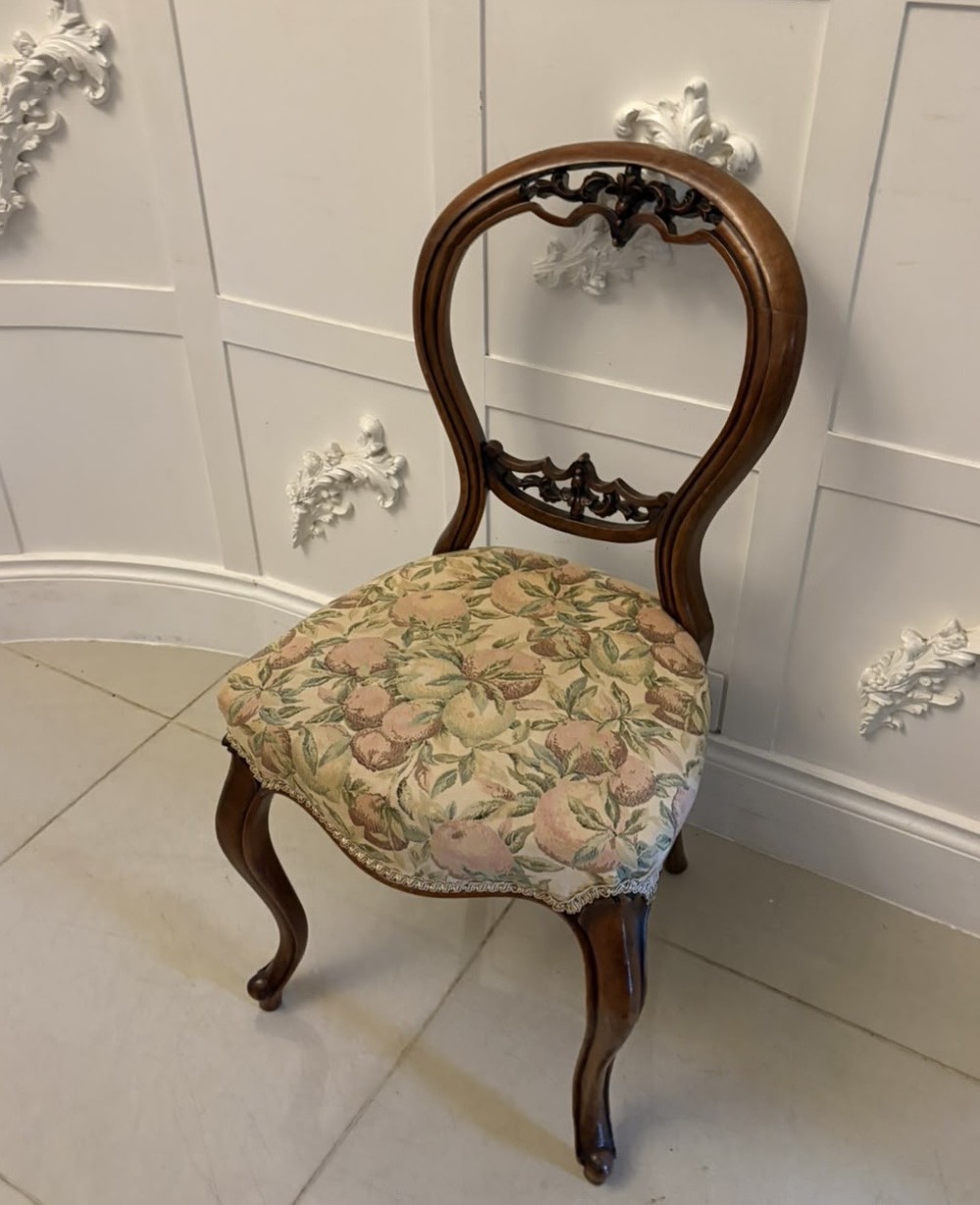 A set of four Victorian carved walnut dining chairs featuring open balloon backs, carved crest details, cabriole front legs, and floral pattern upholstered seats. View VIII