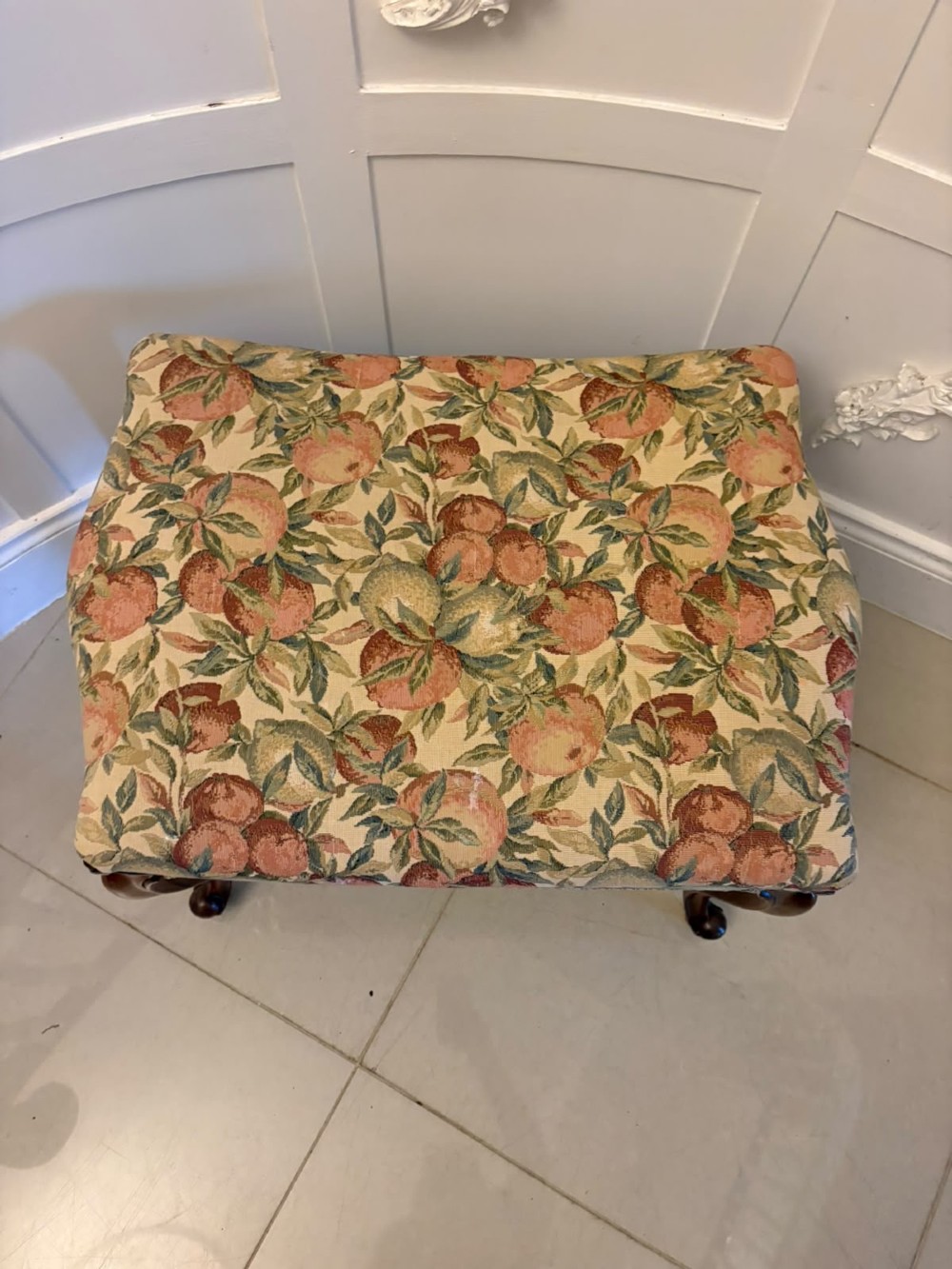 A low rectangular Victorian footstool featuring carved walnut cabriole legs and a padded seat upholstered in a botanical tapestry fabric depicting fruit and foliage. View VII