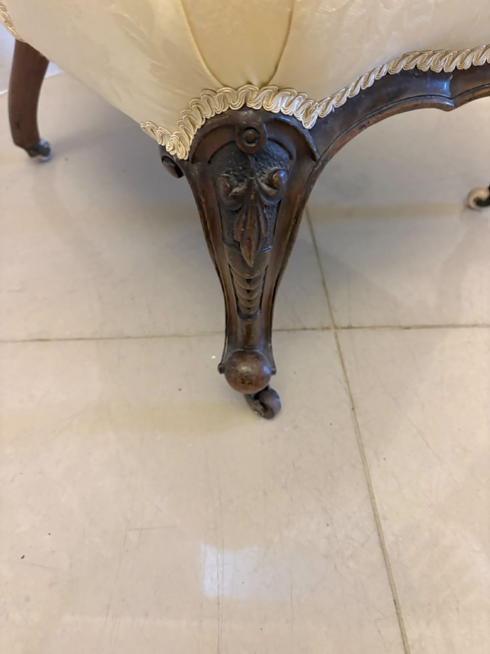 A Victorian carved walnut slipper chair featuring a button-tufted cream damask spoon-shaped backrest and cabriole front legs. View VIII