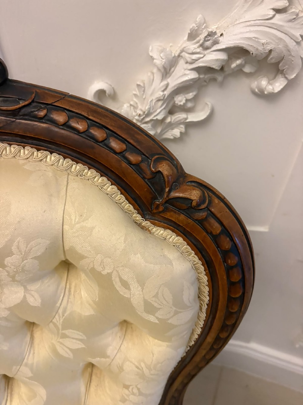A Victorian carved walnut slipper chair featuring a button-tufted cream damask spoon-shaped backrest and cabriole front legs. View X
