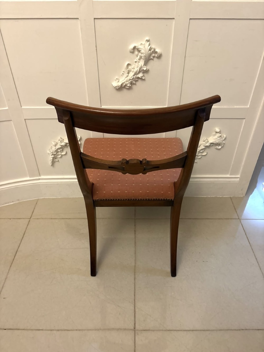 An antique mahogany carver dining chair with sweeping armrests, a carved central roundel crest bar, and a pink patterned upholstered seat. View IX