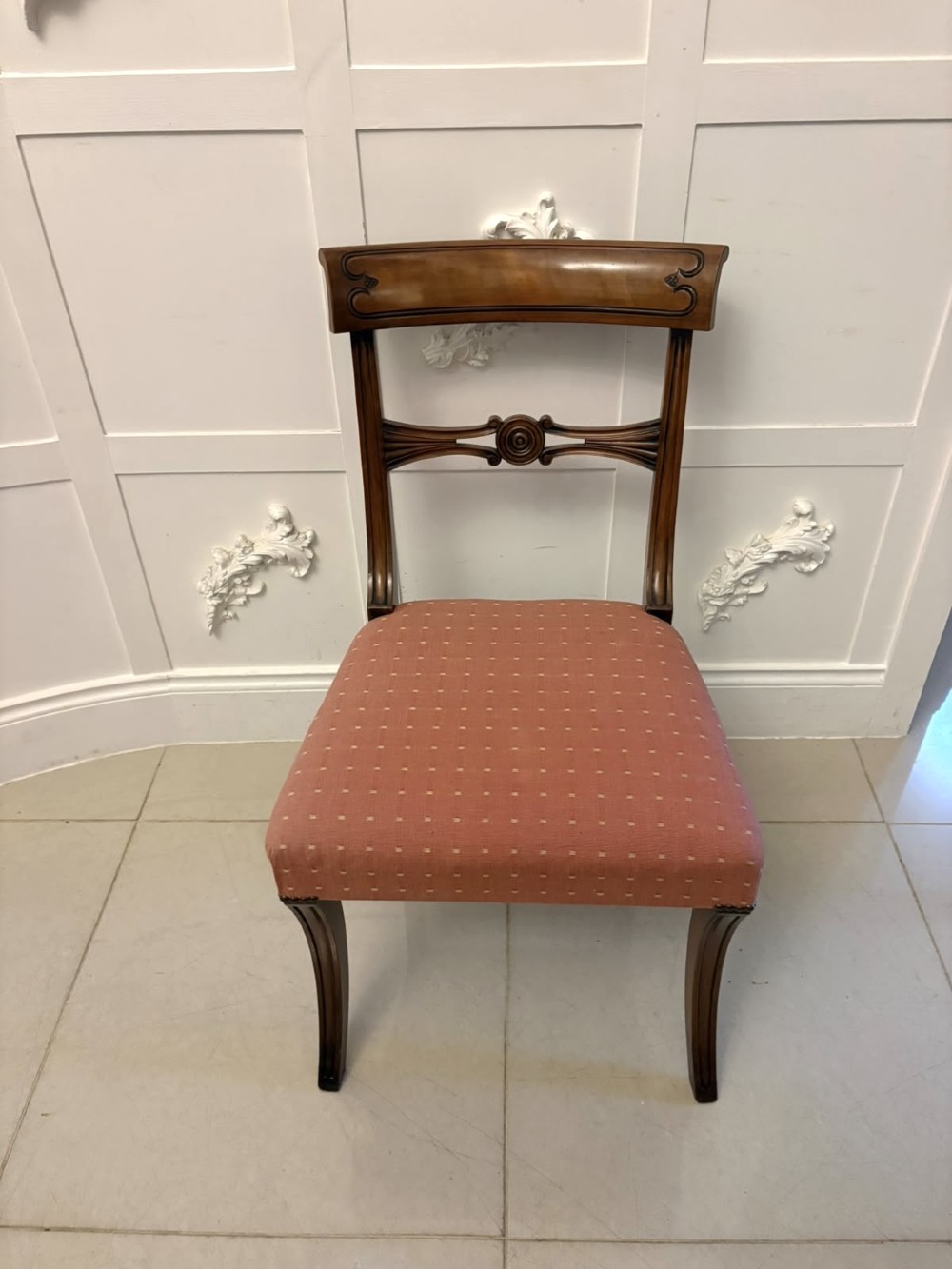 An antique mahogany carver dining chair with sweeping armrests, a carved central roundel crest bar, and a pink patterned upholstered seat. View XI