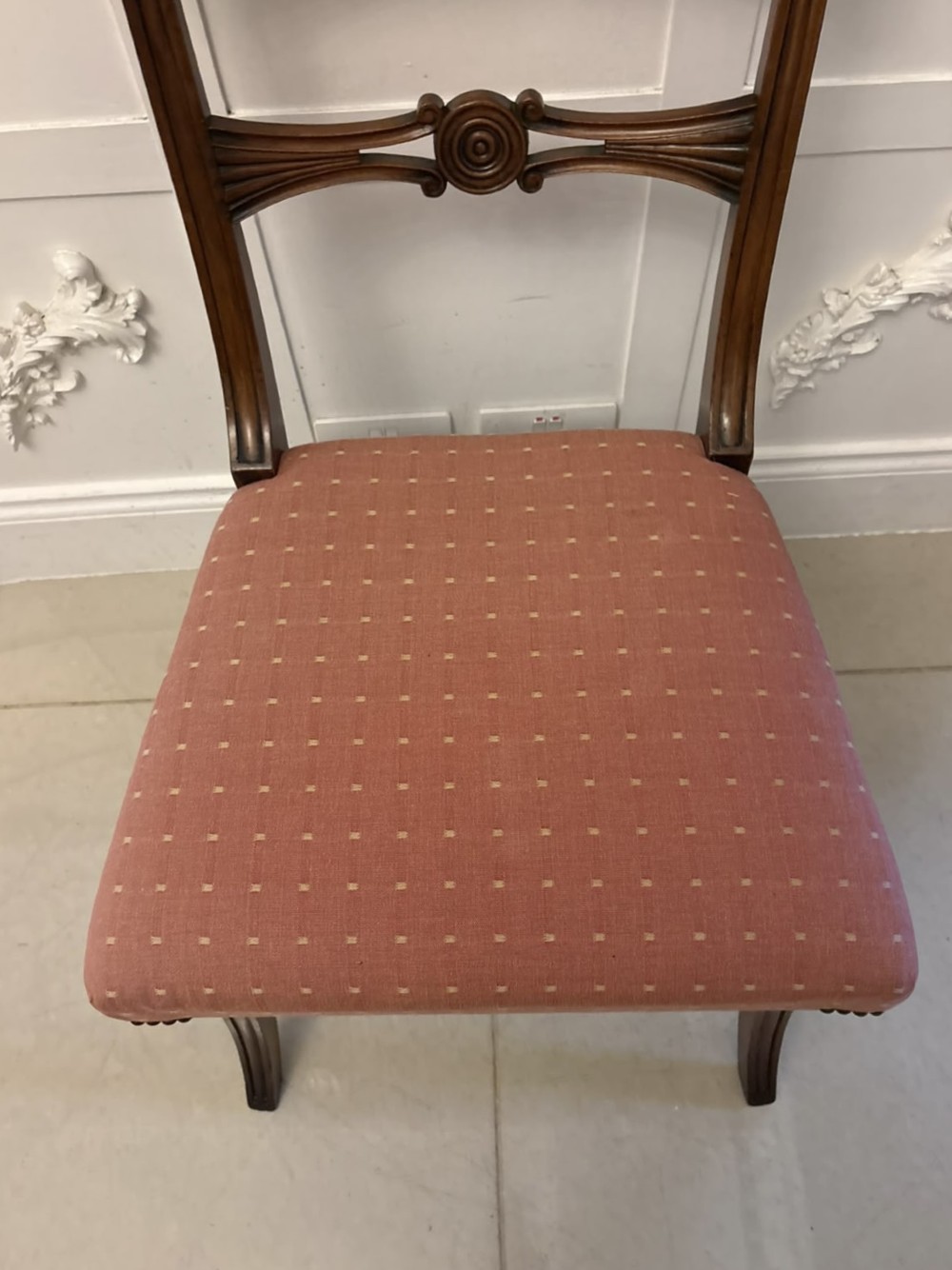 An antique mahogany carver dining chair with sweeping armrests, a carved central roundel crest bar, and a pink patterned upholstered seat. View XIII
