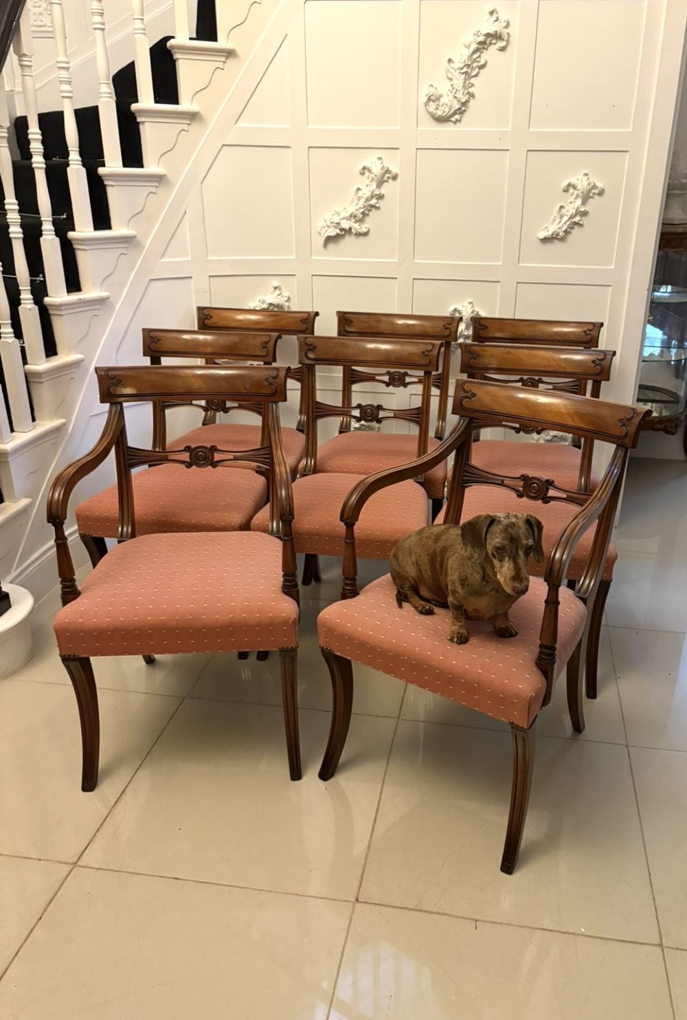 An antique mahogany carver dining chair with sweeping armrests, a carved central roundel crest bar, and a pink patterned upholstered seat. View III