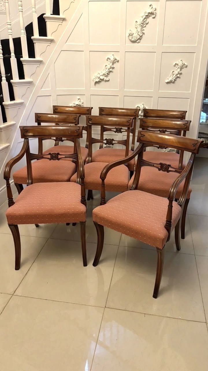 An antique mahogany carver dining chair with sweeping armrests, a carved central roundel crest bar, and a pink patterned upholstered seat.