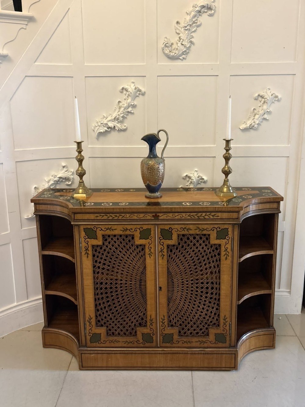 A Sheraton Revival satinwood side cabinet featuring painted leaf borders, central doors with fan-shaped woven cane panels, and open curved side shelves. View V